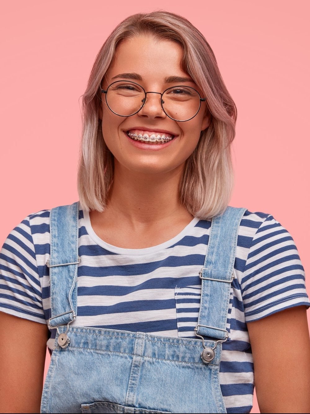 glad smiling pretty female freelancer has broad smile demonstrates teeth with braces wears casual e1619344512298.jpg